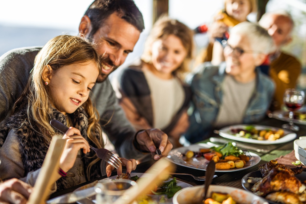 Un homme aide une fille à découper ses aliments lors d'un repas convivial au restaurant L'Évasion.