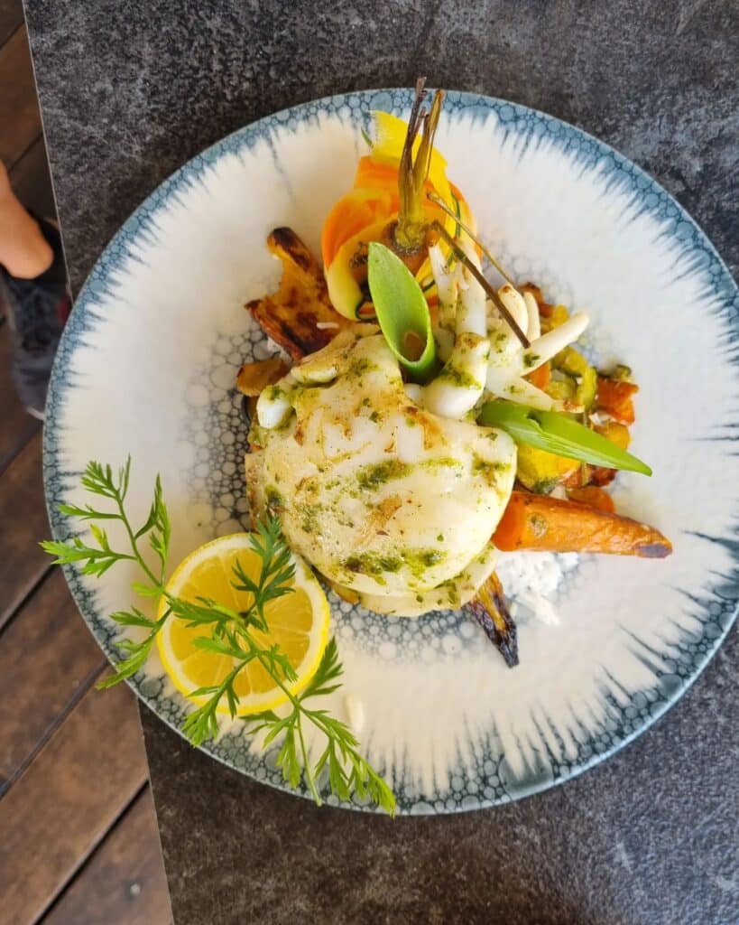 Poisson grillé, légumes sautés, citron, herbes; servi sur assiette bleue à Fréjus.