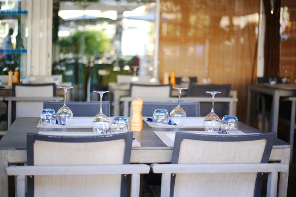 Terrasse extérieure de L'Évasion : tables dressées, verres renversés, poivrières ; bar salon idéal.