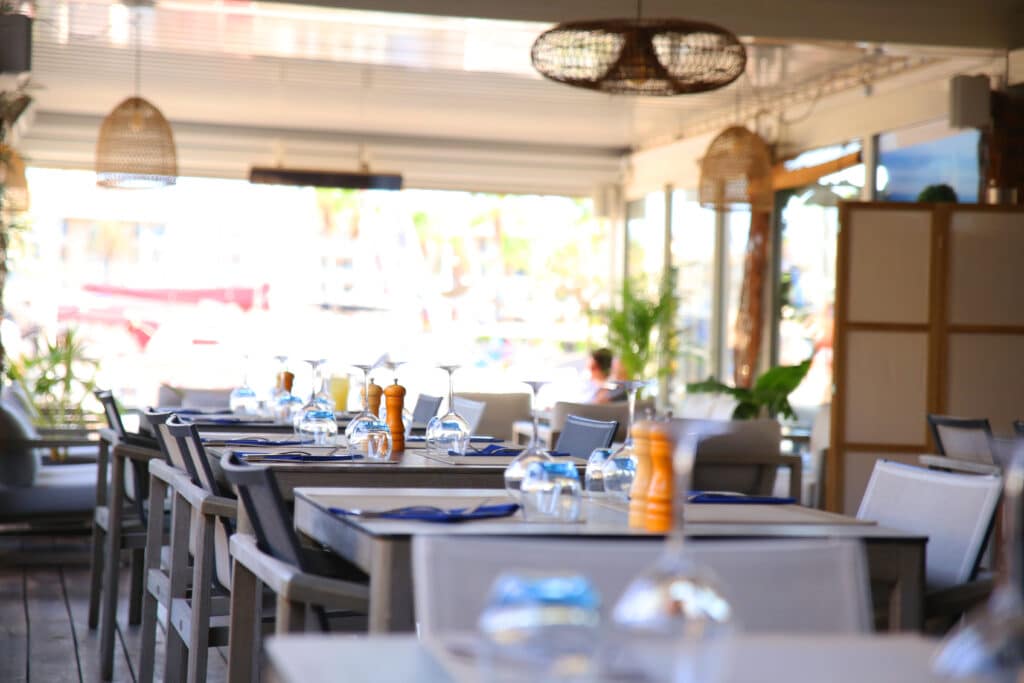 Terrasse conviviale avec tables en bois, ambiance lumineuse et étendue rappelle un bar lounge à Fréjus.