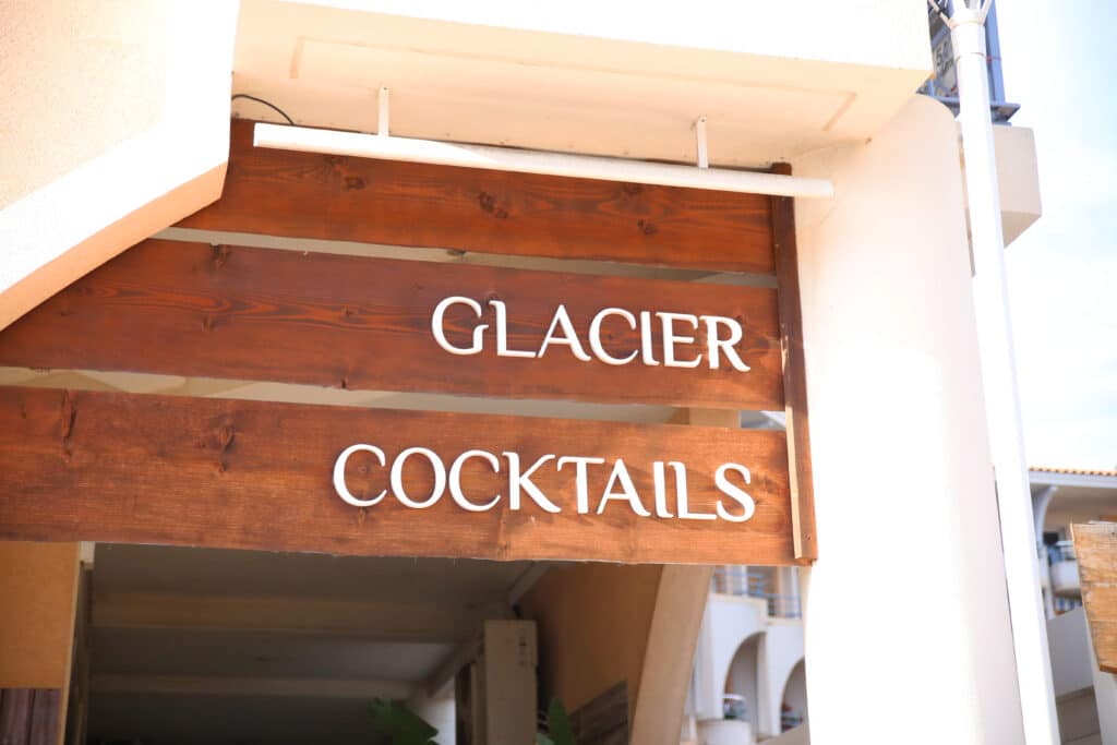 Une pancarte en bois indique « GLACIER COCKTAILS » en blanc.