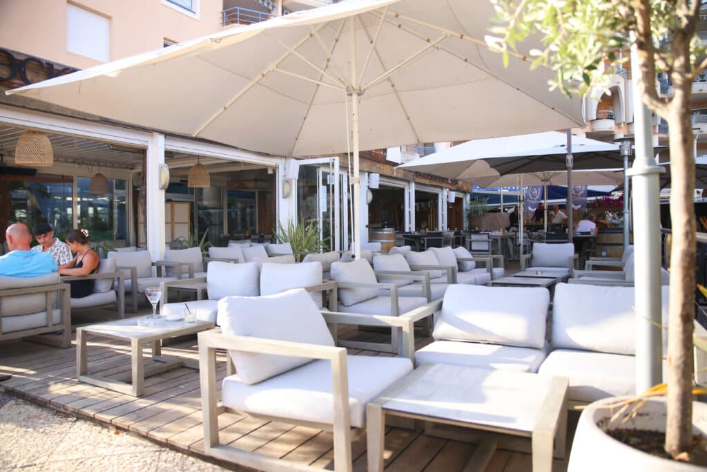 Terrasse de café à Fréjus avec parasols et clients.