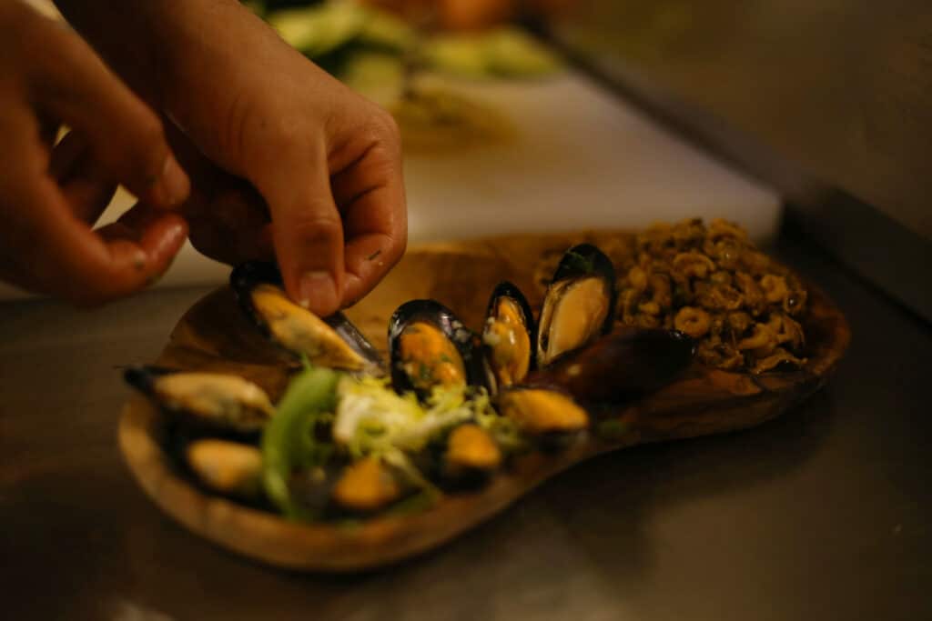 Au port de Fréjus, un serveur garnit des moules fraîches sur une planche en bois.