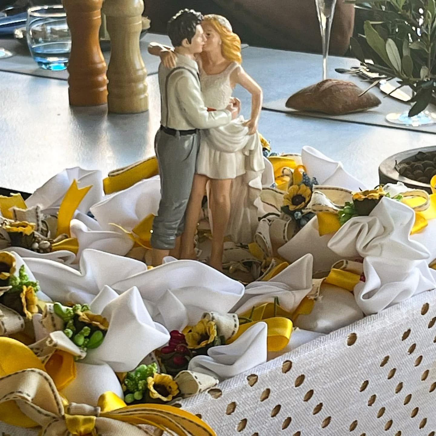 Cake topper couple s'embrassant à L'Évasion, table décorée de rubans et de fleurs.