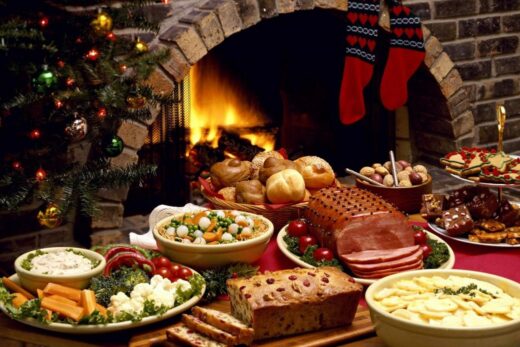 Aliments de fêtes comme le jambon, les desserts et le pain; ambiance festive avec bas et sapin.